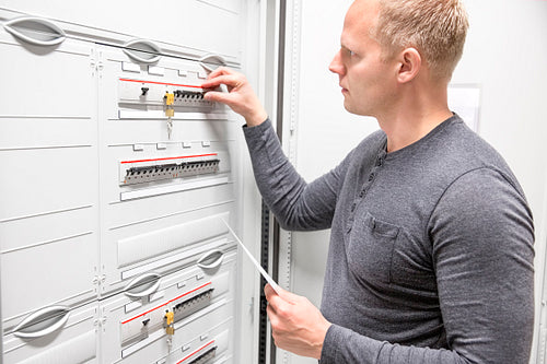 Technician works in large electric fuse cabinet