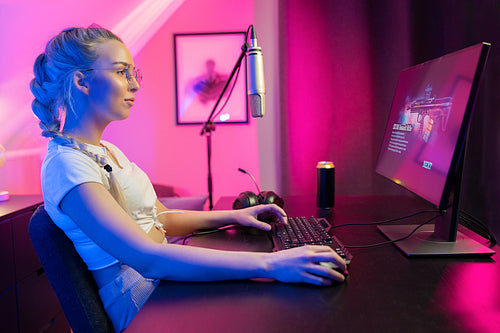 Focused Beautiful Blonde Gamer Girl Playing Online Video Game on Her Personal Computer.