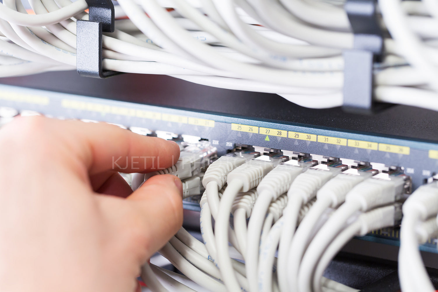 IT consultant connects a network cable into switch in datacenter