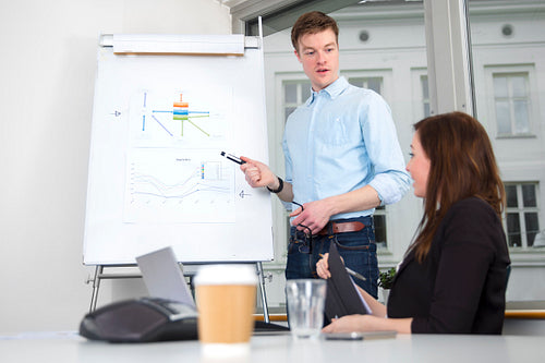 Confident Businessman Giving Presentation To Colleague In Office