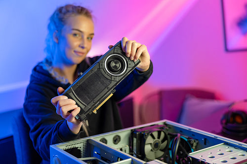 Blonde Gamer Girl Holding a New GPU Video Card in Her Hands