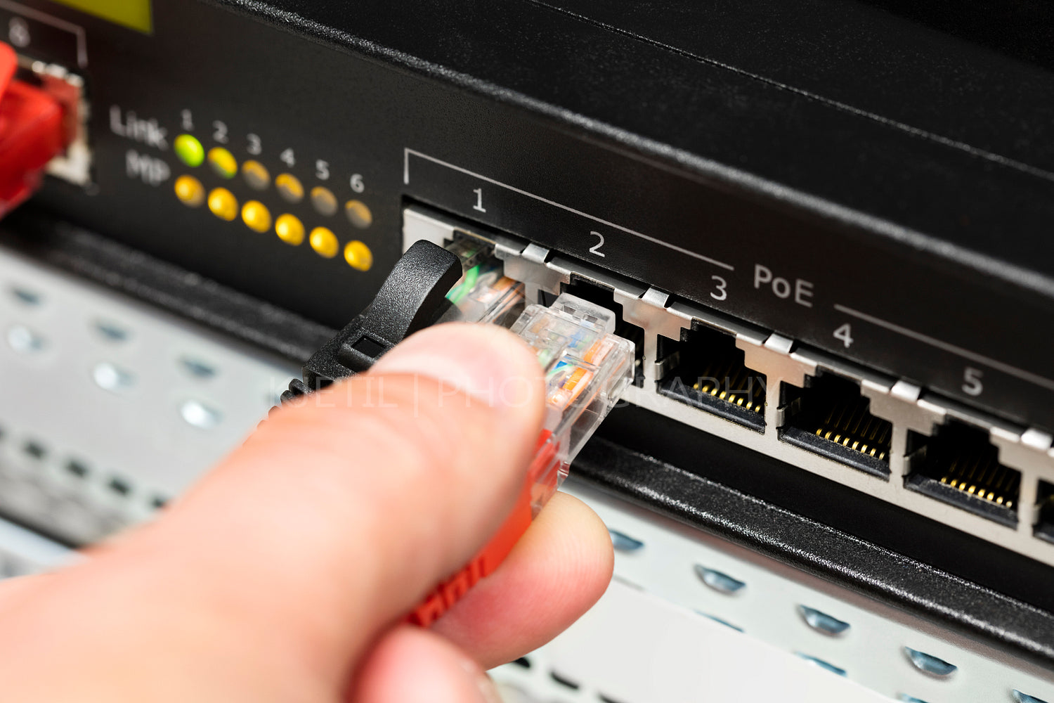 Computer Technician's Hand Inserting Cable Into Switch