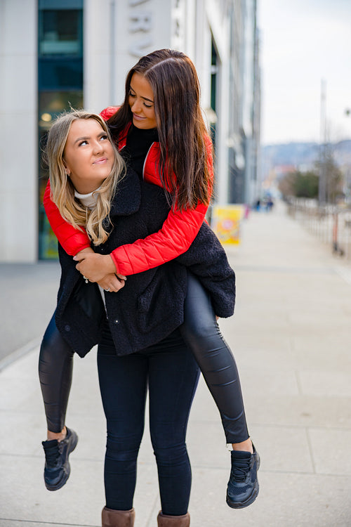 Two Close Woman Friends Having Fun and Piggybacking In City