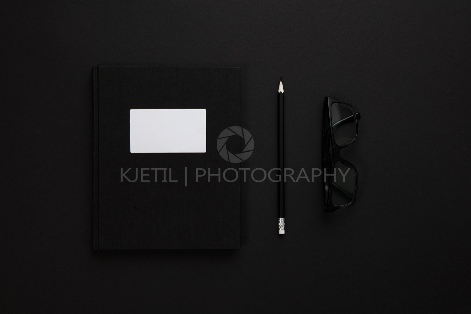 Top view of low key black office desk with notebook and glasses