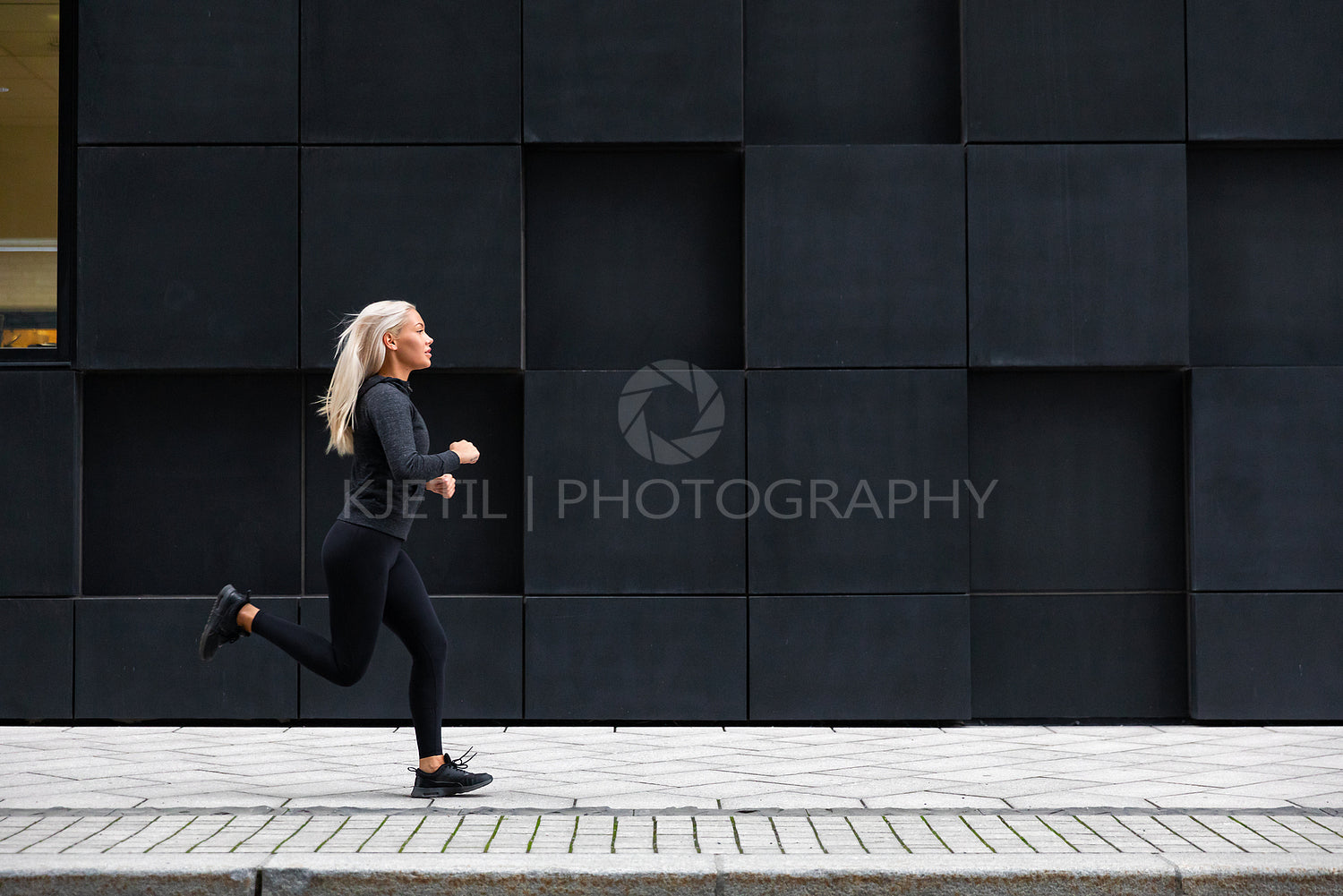 Woman running on the city street against modern city walls
