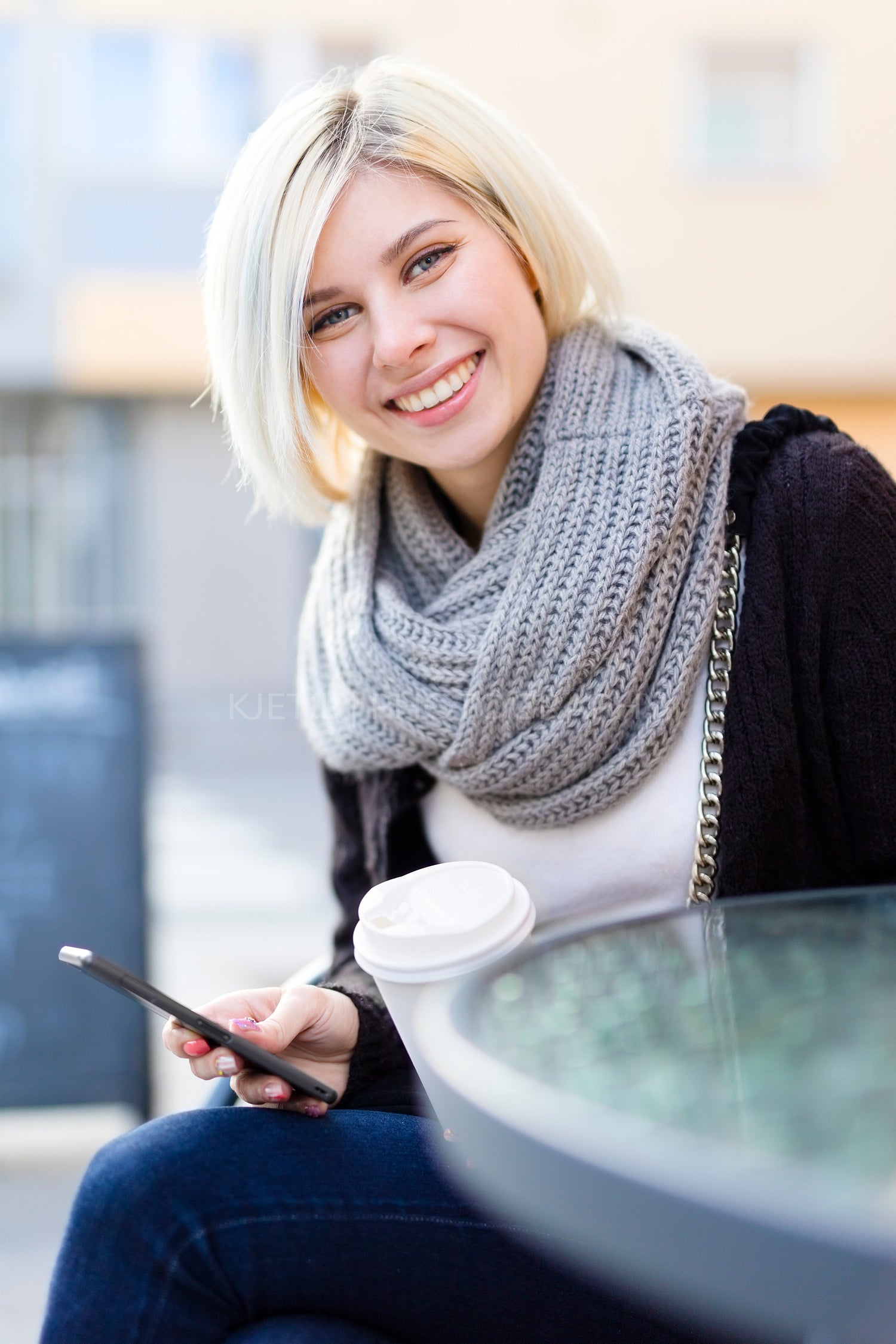 Smiling woman with coffee and using phone outdoor