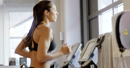 Fit woman in workout clothes running on treadmill machine in fitness gym