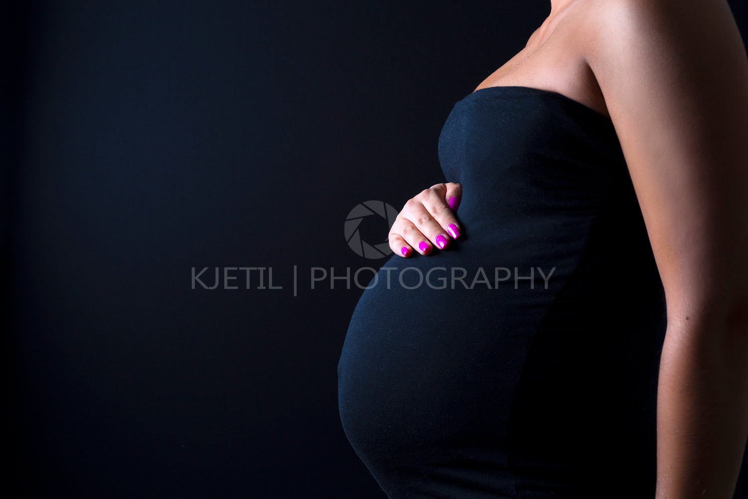 Young pregnant woman stands with her hands at the belly