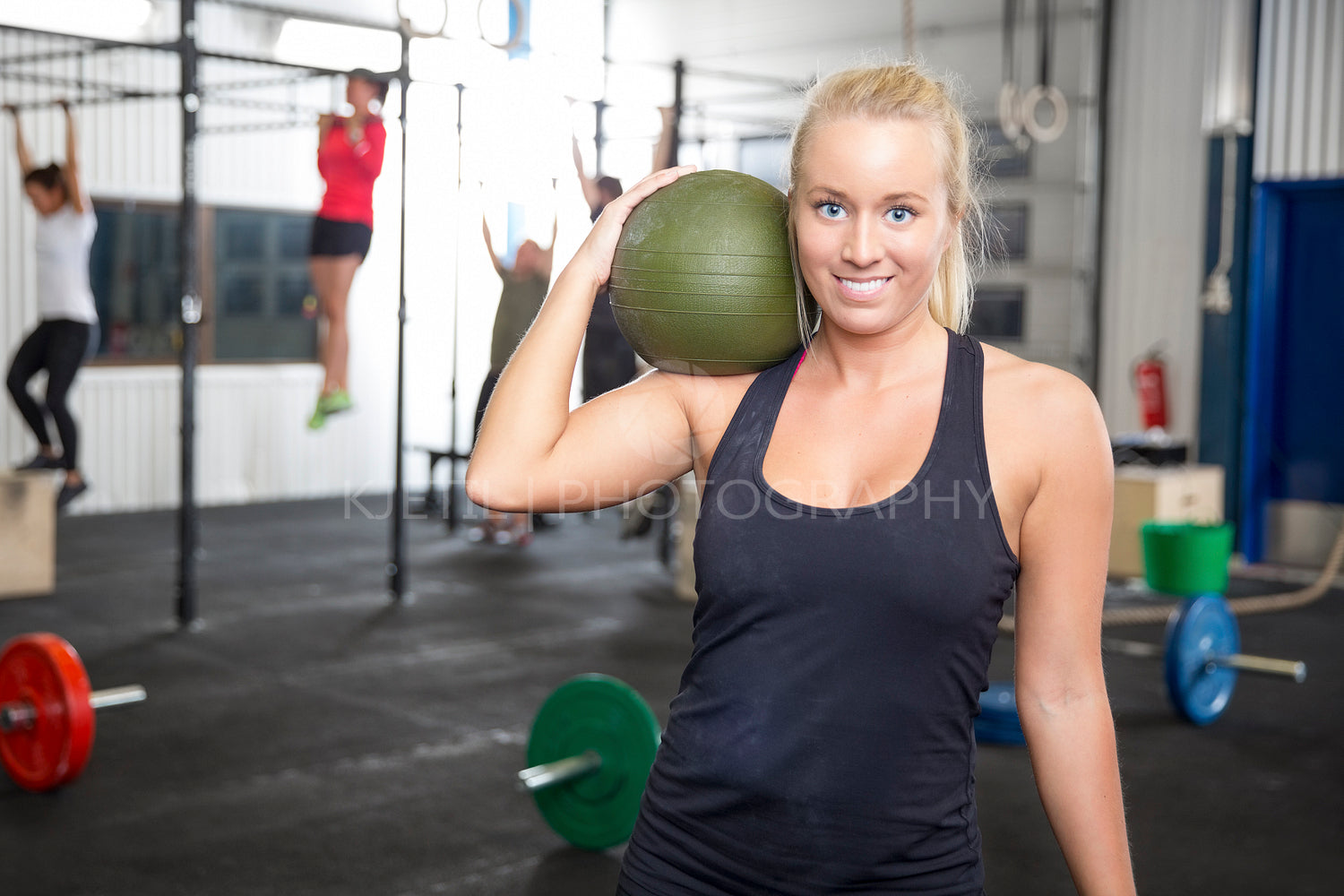 Smiling blonde woman with slam ball at fitness gym
