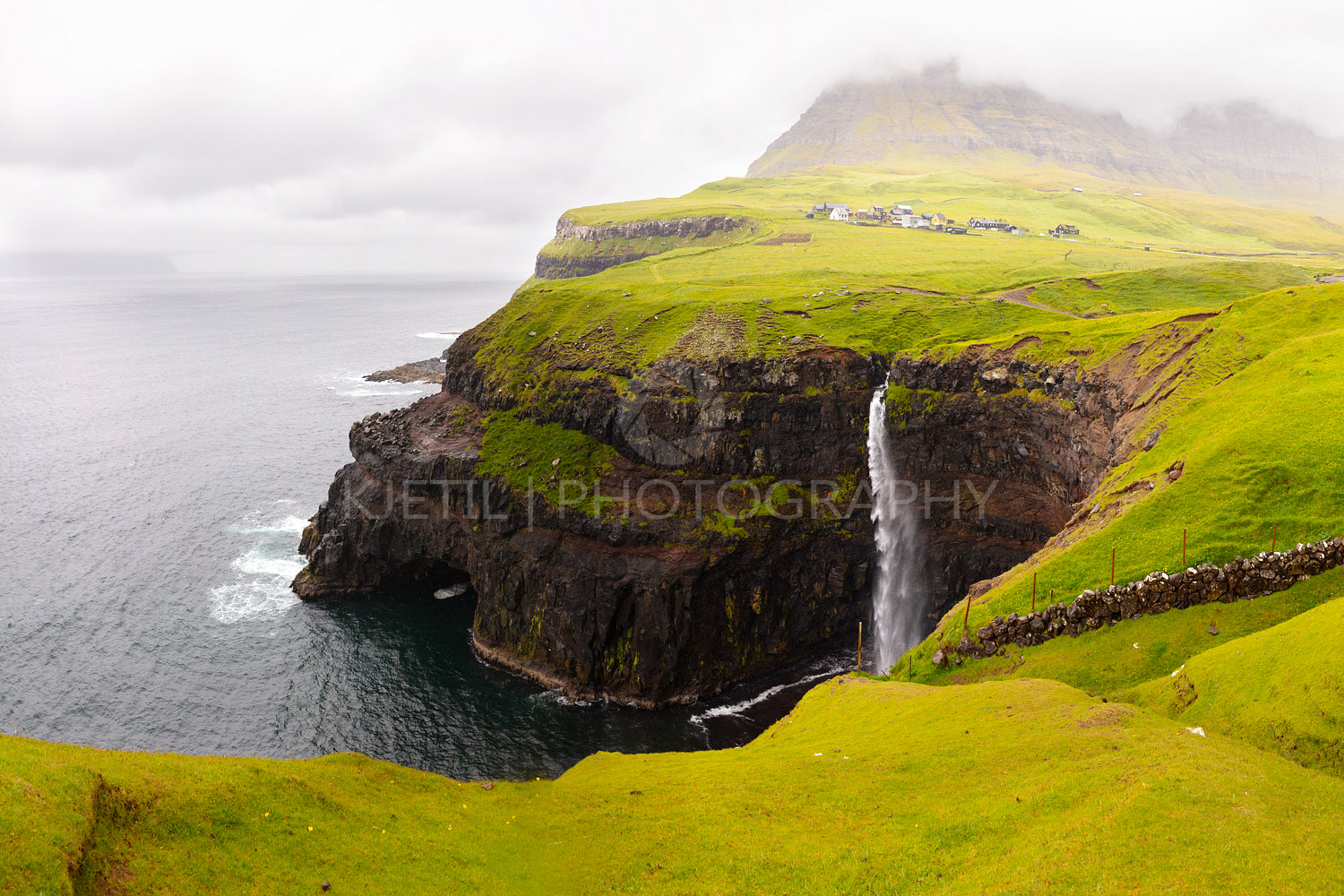 Dramatic waterfall on Faroe Islands and the village Gasadalur
