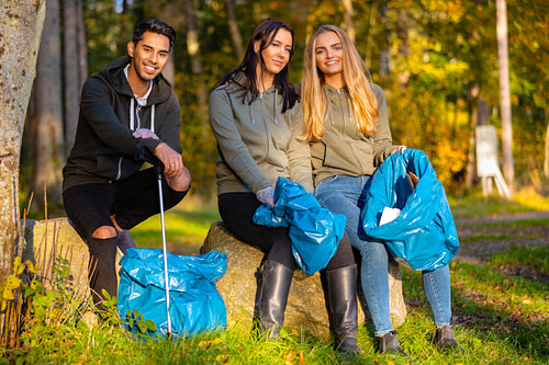Focused team of young volunteers collecting garbage to protect the environment