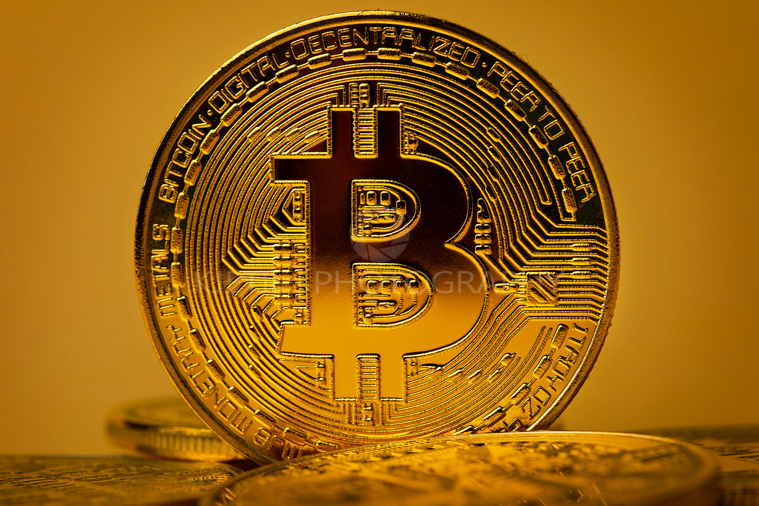 Closeup of shiny gold bitcoin on yellow backgound