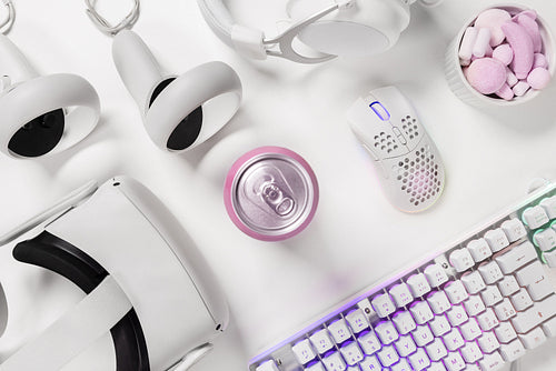 Modern gaming gadgets with drink can on white desk