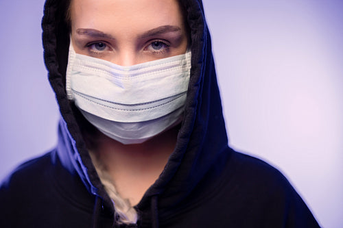 Serious caucasian woman in protective face mask with blue color lights