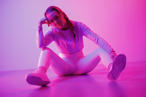 Woman in sportswear against illuminated purple background