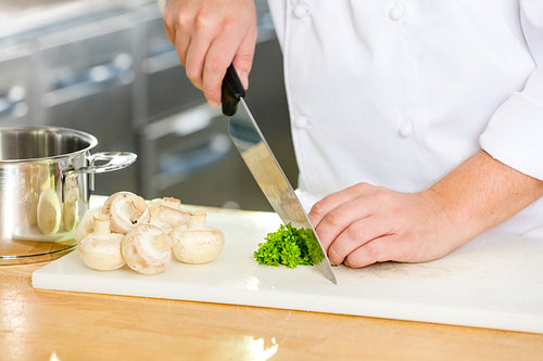 Professional chef cutting parley and mushrooms