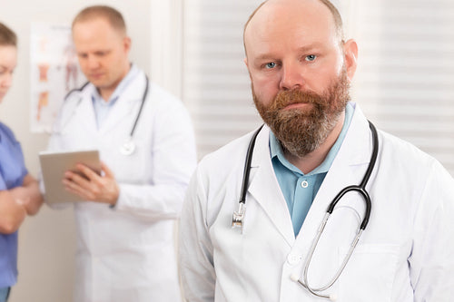Portrait of a confident real doctor standing in front of his health team
