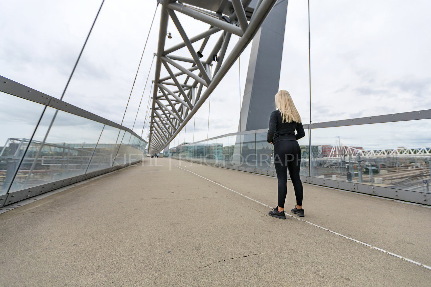 Fitness woman runner Standing On Bridge in Modern Looking City
