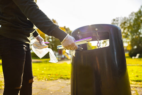 Volunteer putting straws in garbage bin at park