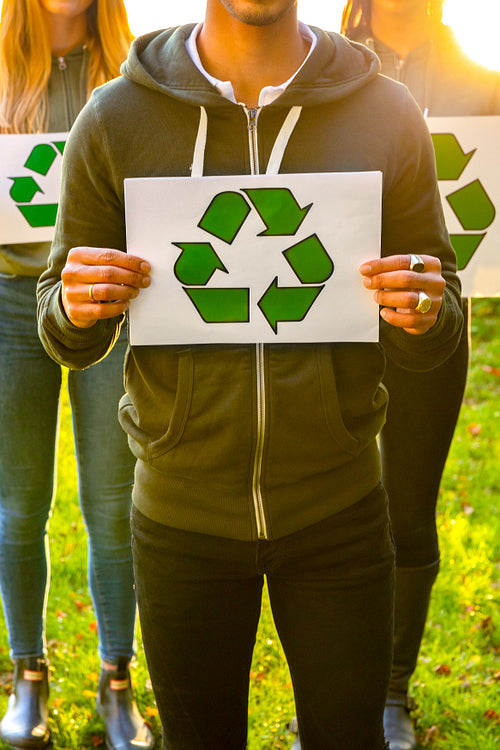 Team of volunteers holding recycling symbol placards outdoor