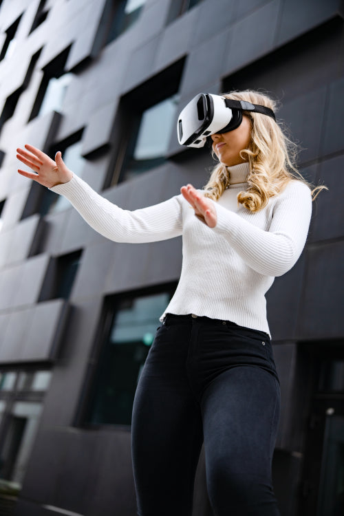 Woman Wearing Virtual Reality Glasses Against Contemporary City Building