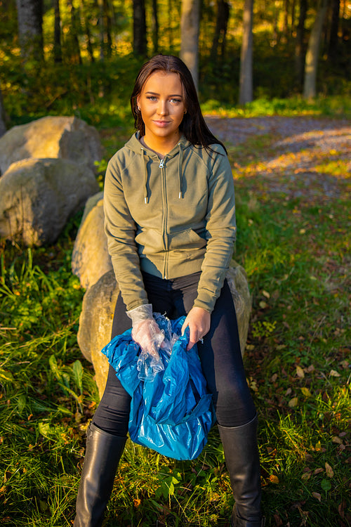 Female in environmental protection team volunteer holding garbage bag and taking a break