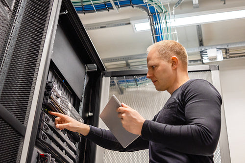 Male IT Technician Holding Digital Tablet Analyzing Servers in Datacenter