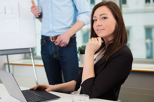 Businesswoman Using Laptop While Colleague Giving Presentation