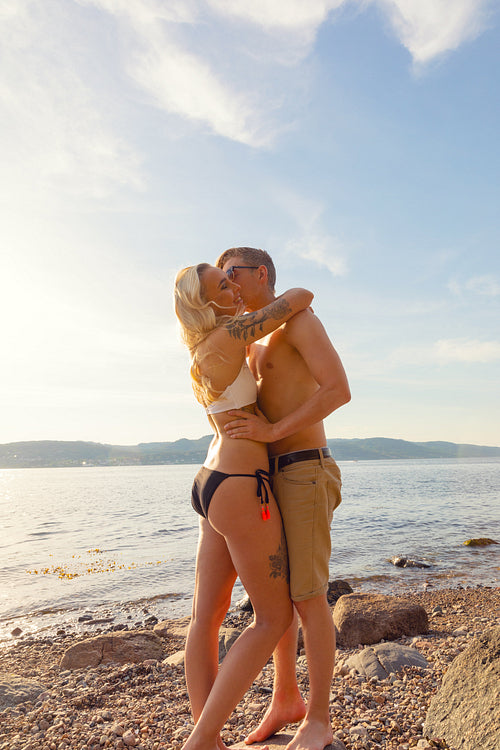 Young Couple Standing On Rock And Holding Each Other At Beach