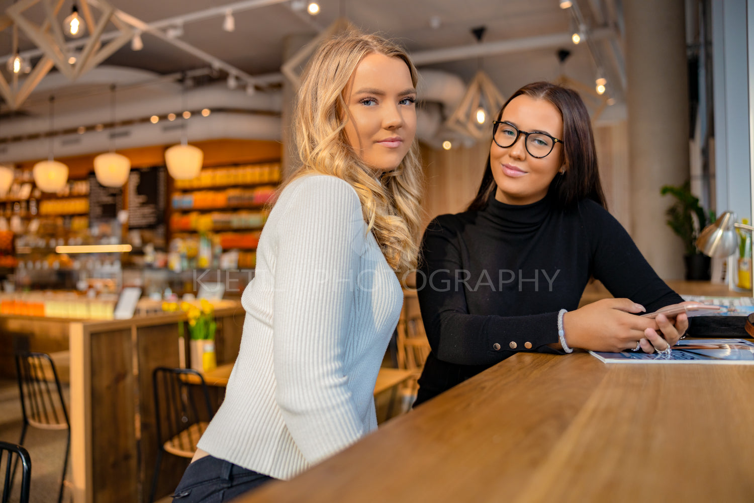 Two Urban Female Friends Looking At Camera in Cafe