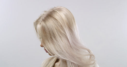 Slow motion studio portrait of a blonde woman's hair blowing in the wind