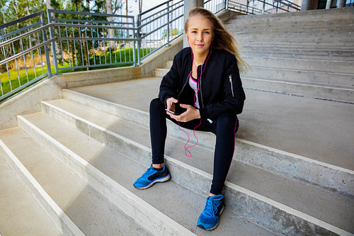 Young Woman In Sportswear Listening Music On Smartphone