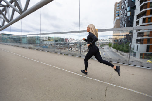 Female jogger in black workout outfit in modern city environment