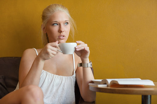 Young blonde woman drinking coffee at cafe