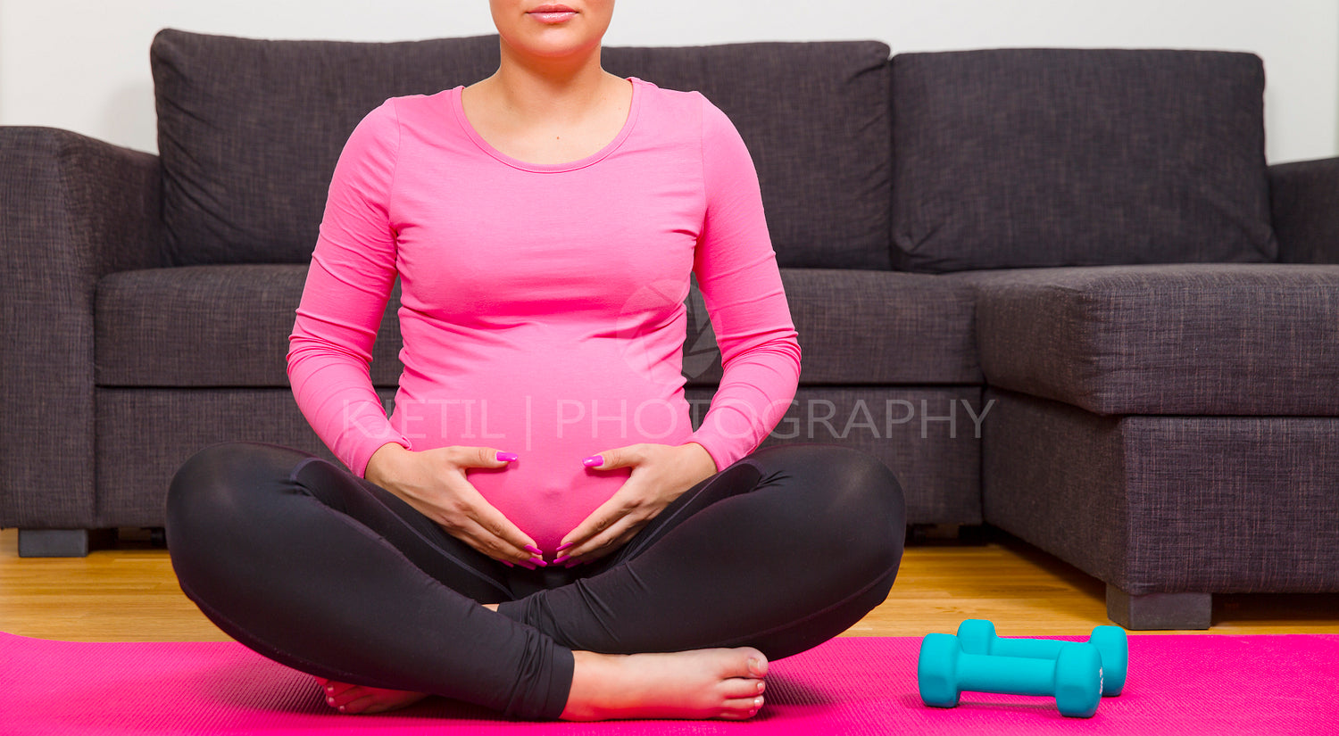 Pregnant woman exercising and holds her belly