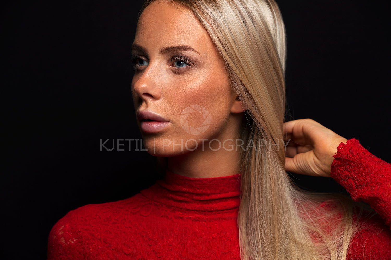 Dark portrait of a beautiful blonde woman in red dress with black bakground