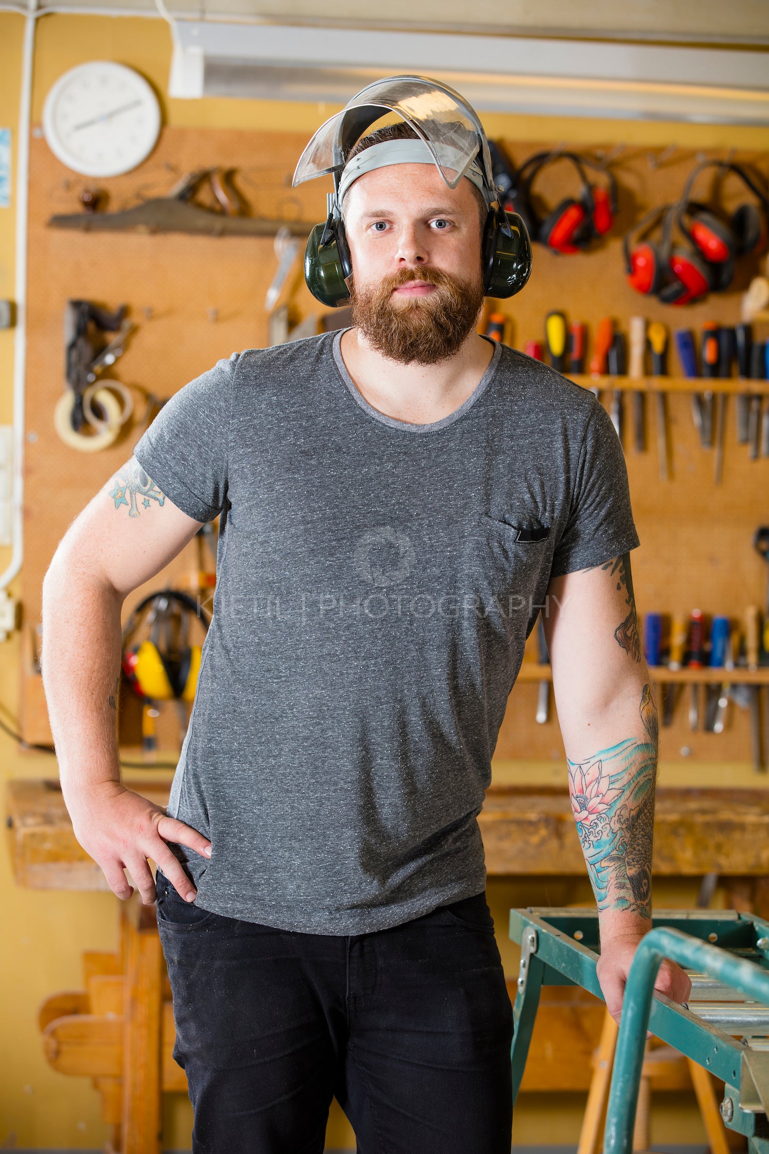 Confident craftsman with safety mask and earmuffs in workshop
