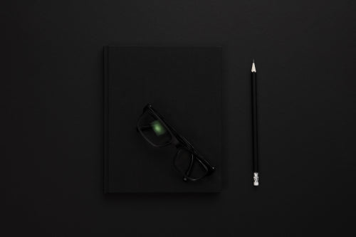Top view of low key black office desk with notebook and supplies