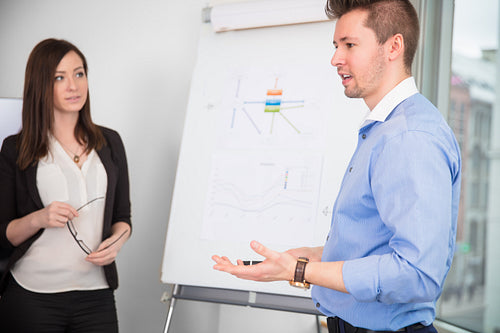 Businessman Giving Presentation While Colleague Looking At Him