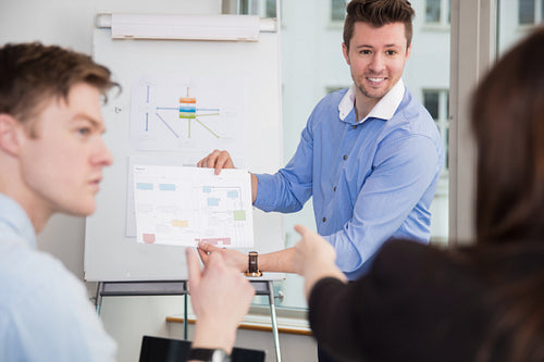Smiling Professional Showing Chart To Colleagues