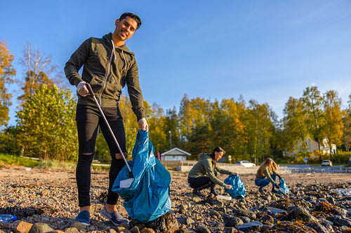 Man cleaning beach with volunteers on sunny day