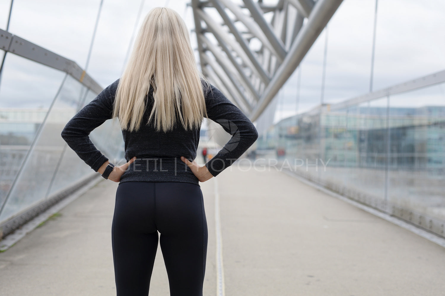 Fit blonde woman runner standing on bridge in modern looking city