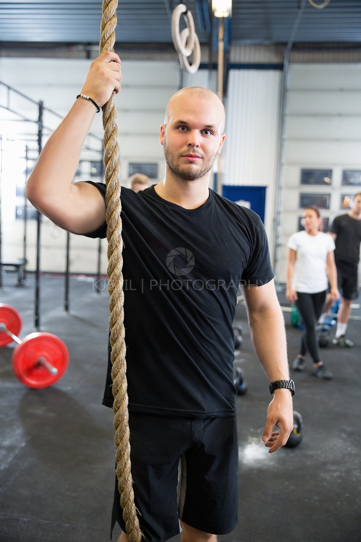 Confident Male Athlete Holding Gym Rope In Health Club