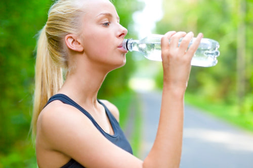 Woman runner drinking water after running