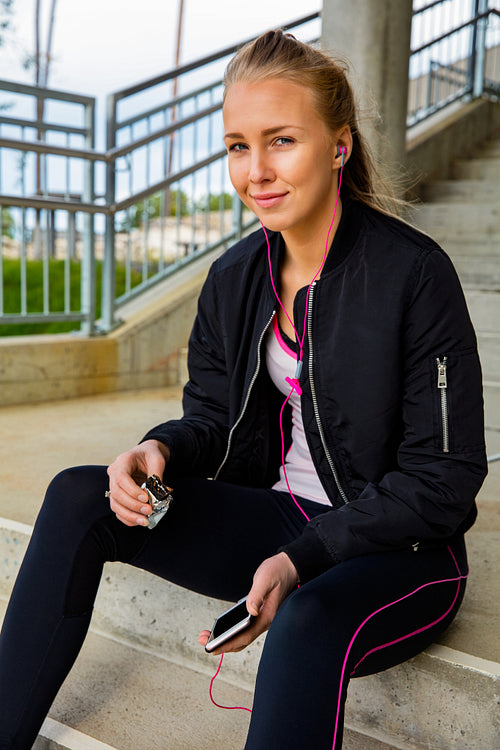 Sporty Woman Holding Protein Bar And Smart Phone On Steps
