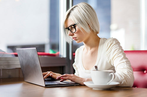 Young focused woman working with laptop computer in cafe