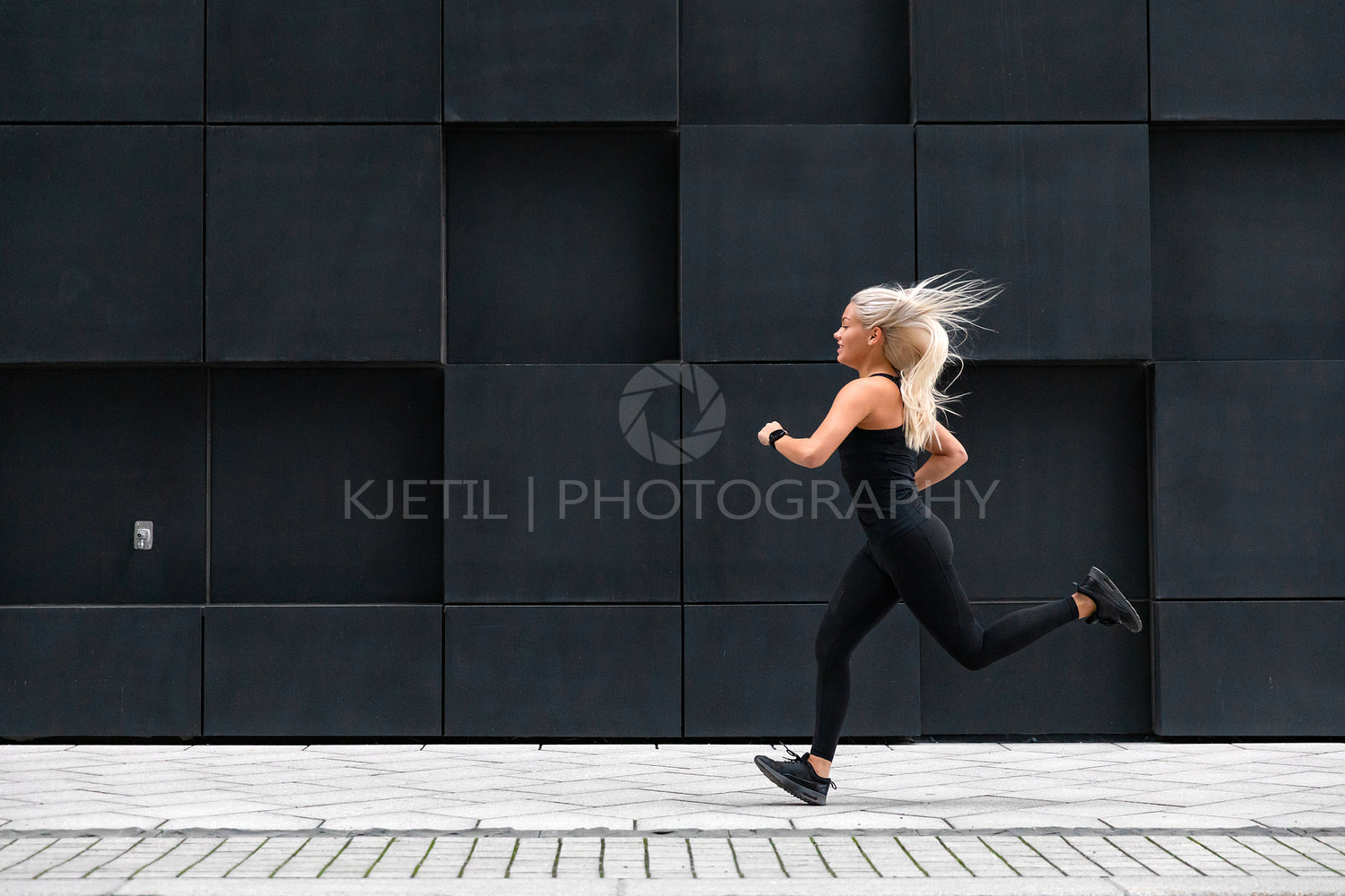 Side view of sporty young woman running fast in minimalist urban environment