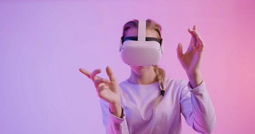 Beautiful woman using VR headset and moving hands in colored room
