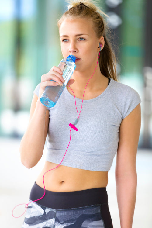 Woman drinks water after workout outdoor in the city