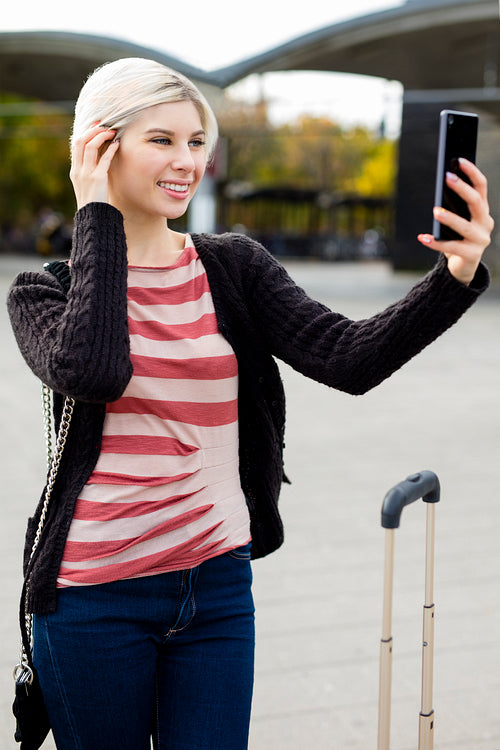 Woman Taking Selfie With Mobile Phone Outside Railroad Station
